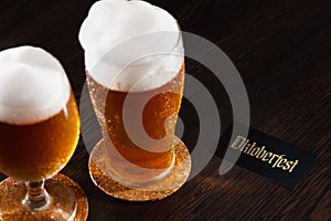 Beer glass pint on a wooden background with foam and Oktoberfest text.