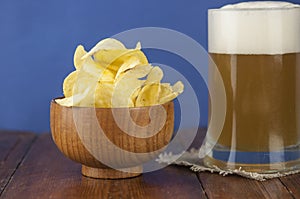 Beer glass with beer and smoked fish close-up. Beer mug with beer and potato chips, crackers on a wood background and copy space