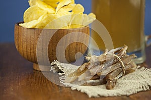 Beer glass with beer and smoked fish close-up. Beer mug with beer and potato chips, crackers on a wood background and copy space