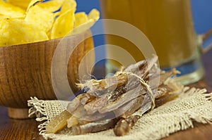 Beer glass with beer and smoked fish close-up. Beer mug with beer and potato chips, crackers on a wood background and copy space