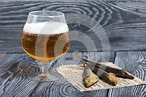 Beer in a glass and smoked fish. On pine boards. A day without diets