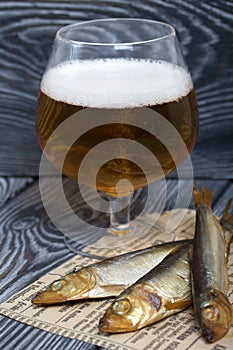 Beer in a glass and smoked fish. On pine boards. A day without diets