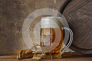 Beer mug with wheat ears and wooden barrel on a dark wall background, pour beer