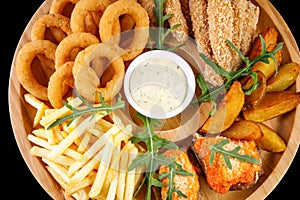 Beer plate fried ribs onion rings french fries fish nuggets on a wooden plate on a black background3
