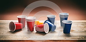Beer pong. Plastic red and blue color cups and ping pong balls on wood, banner