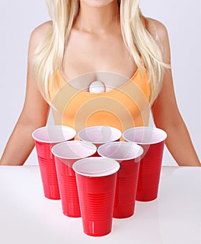 Beer pong. Red plastic cups with ping pong ball and blonde girl in tank top photo