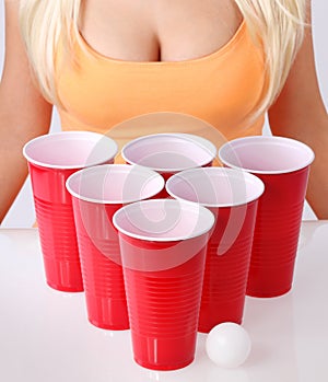 Beer pong. Red plastic cups with ping pong ball and blonde girl in tank top
