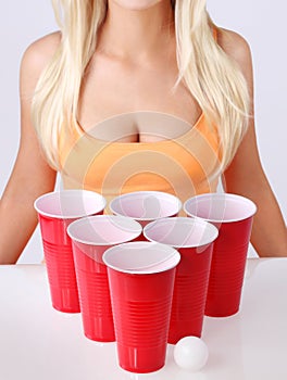 Beer pong. Red plastic cups with ping pong ball and blonde girl in tank top