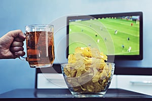 Beer potato chips and Sport on TV, A man raises a mug of dark beer celebrate the victory of his favorite team in the world Cup,
