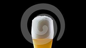Beer is poured into the glass on a black background. Beer is poured into a glass. Glass with beer slow moving HD frames