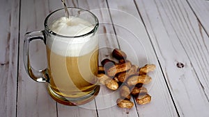 Beer pouring into mug and peanuts