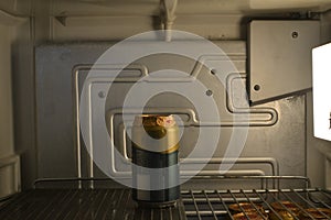 Beer in the refrigerator, open vintage refrigerator showing the inside with internal light and shelf with cold beer can