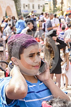 Beer-Sheva, ISRAEL - March 5, 2015:Portrait of a teenage boy in a blue T-shirt with purple red hair with a mobile phone in a crowd