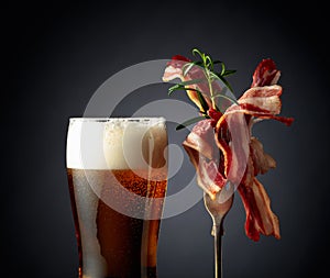 Beer and slices of  fried bacon garnished with rosemary