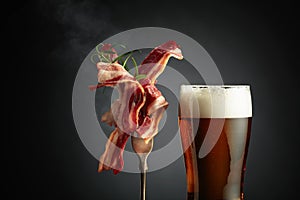 Beer and slices of fried bacon garnished with rosemary