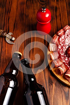 Beer snack in the form of meat products and bottled beer. Appetizer in the form of slicing bacon, salami, ham, hunting sausages.