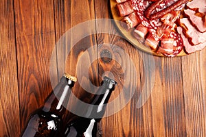 Beer snack in the form of meat products and bottled beer. Appetizer in the form of slicing bacon, salami, ham, hunting sausages.