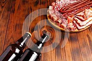 Beer snack in the form of meat products and bottled beer. Appetizer in the form of slicing bacon, salami, ham, hunting sausages.