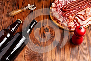 Beer snack in the form of meat products and bottled beer. Appetizer in the form of slicing bacon, salami, ham, hunting sausages.