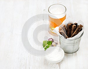 Beer snack set. Pint of pilsener in glass mug and rye bread croutons with garlic cream cheese sauce over white painted