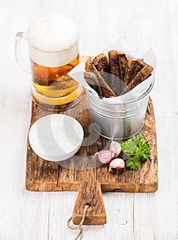 Beer snack set. Pint of pilsener in mug, open glass bottle, rye bread croutons with garlic cream cheese sauce and fresh