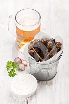Beer snack set. Pint of pilsener in mug and rye bread croutons with garlic cream cheese sauce, fresh parsley over white photo
