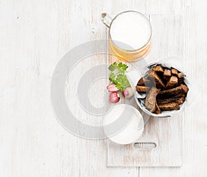 Beer snack set. Pint of pilsener in mug and rye bread croutons with garlic cream cheese sauce over white painted old