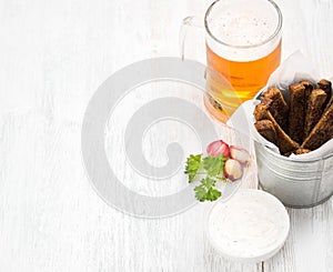 Beer snack set. Pint of pilsener in mug and rye bread croutons with garlic cream cheese sauce over white painted old