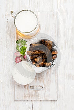 Beer snack set. Pint of pilsener in mug and rye bread croutons with garlic cream cheese sauce served fresh herb over photo