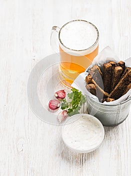 Beer snack set. Pint of pilsener in tall mug and rye bread croutons with garlic cream cheese sauce over white painted photo