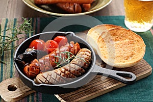 A Glass of Beer and grilled sausage and vegetables with toasted muffins