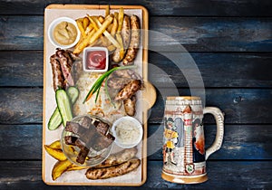 Beer snacks set. Grilled sausages and french fries with tomato and BBQ sauce, served on cutting board with the antique