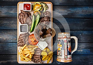 Beer snacks set. Meat set served on cutting board with the antique mug, on the wooden background.