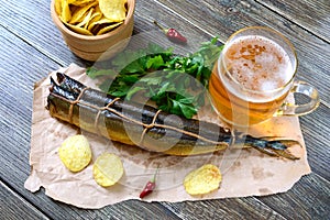 Beer snacks. Smoked fish, chips, a glass of lager beer on a wooden table