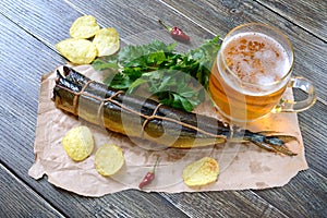 Beer snacks. Smoked fish, chips, a glass of lager beer on a wooden table