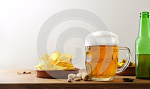 Beer and snacks on wooden bench and white isolated background