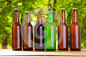 Beer on table on blurred park background, summer drinks,many coloured bottles