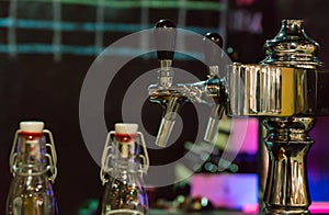 Beer taps in row at restaurant or pub near empty beer bottles