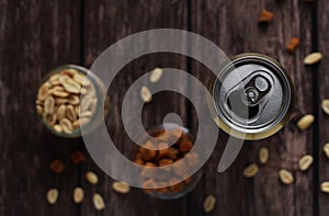 beer in a tin can on a wooden background with crackers and peanuts top view