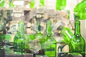 Beer or wine bottles on the conveyor belt. Bottling alkoholic drink. Bottles filled with wine by an industrial machine in a winery
