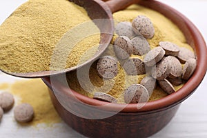 Beer yeast powder and pills on white table, closeup