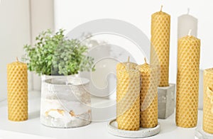 beeswax candles for home decor on a shelf with concrete flower pots. hand made candles made of natural wax with honey