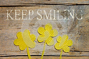Beeswax, three flowers on wooden table, keep smiling