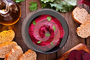 Beet hummus dip, overhead table scene with bread and ingredients on wood