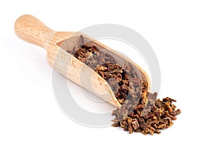 Beet propolis granules in a wooden spoon are on a white background. Natural antibiotic. Beekeeping product