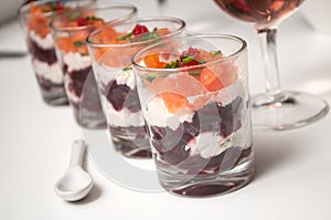 Beet and salmon appetizers in little glasses on white background