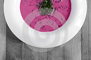 Beet-vegetable soup with greens on a white plate black and white background close-up