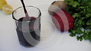 Beetroot juice garnished with mint leaves and slices pouring in a clear glass