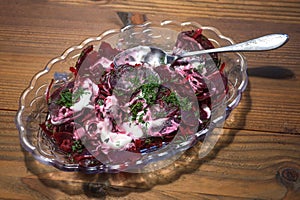 Beetroot salad with dill and a creamy dressing, healthy vegetarian dish in a glass bowl on a rustic wooden table, selected focus