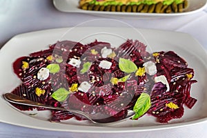 Beetroot slices with feta cheese, basil leaves and a spoon.